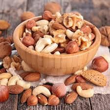 Frutos secos variados en bol y sobre mesa de madera.